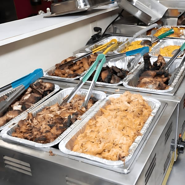 A buffet line at Bill's Grill Smokehouse with various BBQ meats and sides in foil pans.
