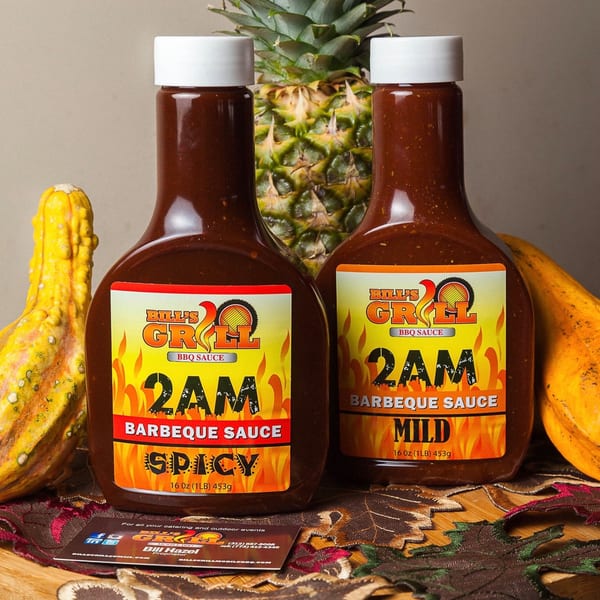 Two bottles of Bill's Grill 2AM BBQ Sauce, spicy and mild, with pineapple and gourds.