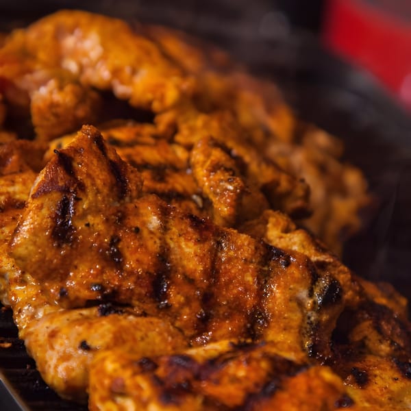 Close-up of Bill's Grill Smokehouse BBQ chicken with grill marks, glistening with sauce.