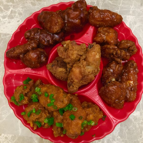 A red platter with compartments filled with various Bill's Grill Smokehouse chicken wings.