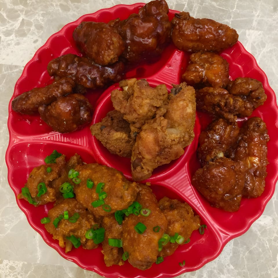 A red platter with compartments filled with various Bill's Grill Smokehouse chicken wings.